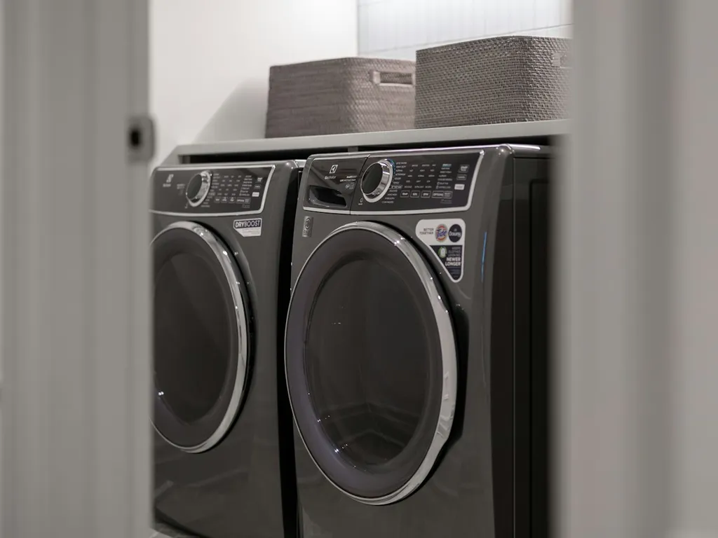 Illustrative photo of a charcoal front-load washer and dryer side by side in a laundry closet